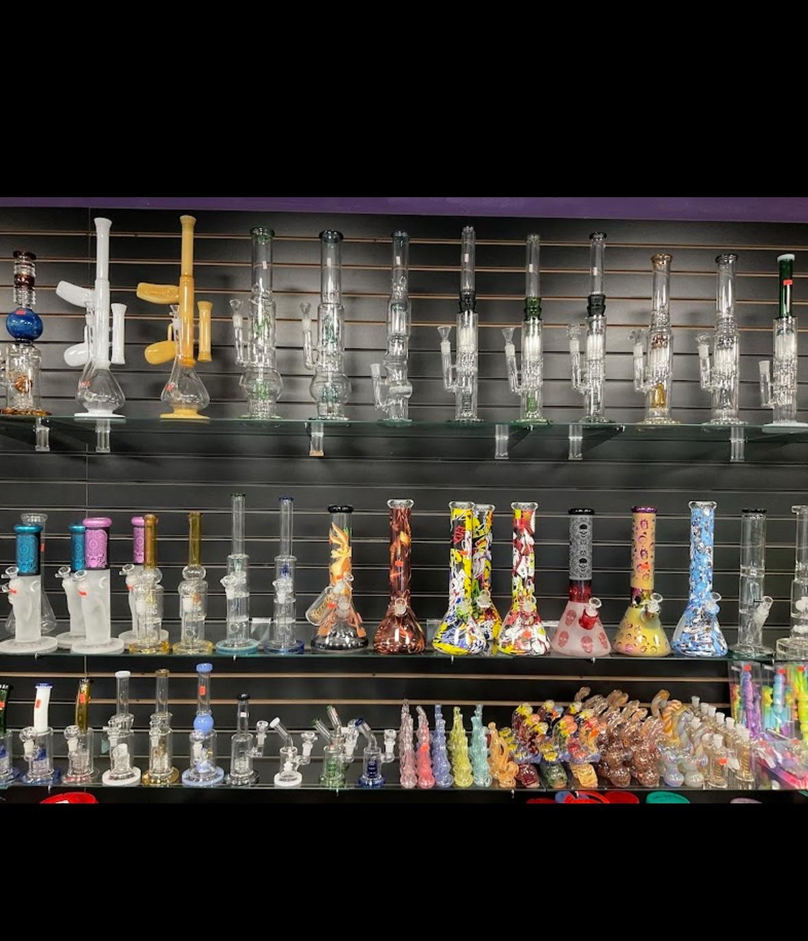 Glass smoking devices and water pipes displayed on shelves in various colors