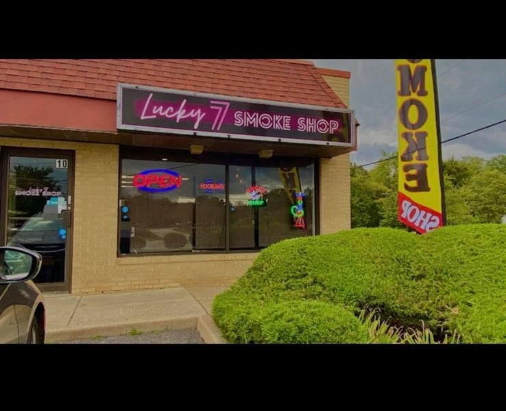 Lucky 7 Smoke Shop storefront with neon signs and open flag