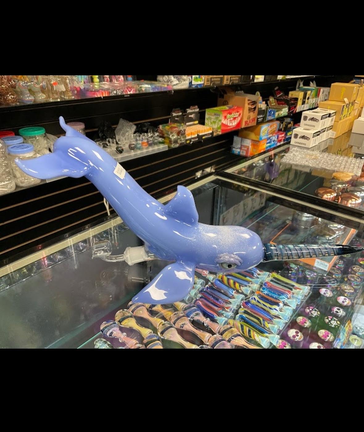 Blue glass dolphin figurine displayed on shelf among colorful merchandise